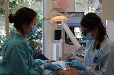 Photo showing a dentist and assistant examining a patient