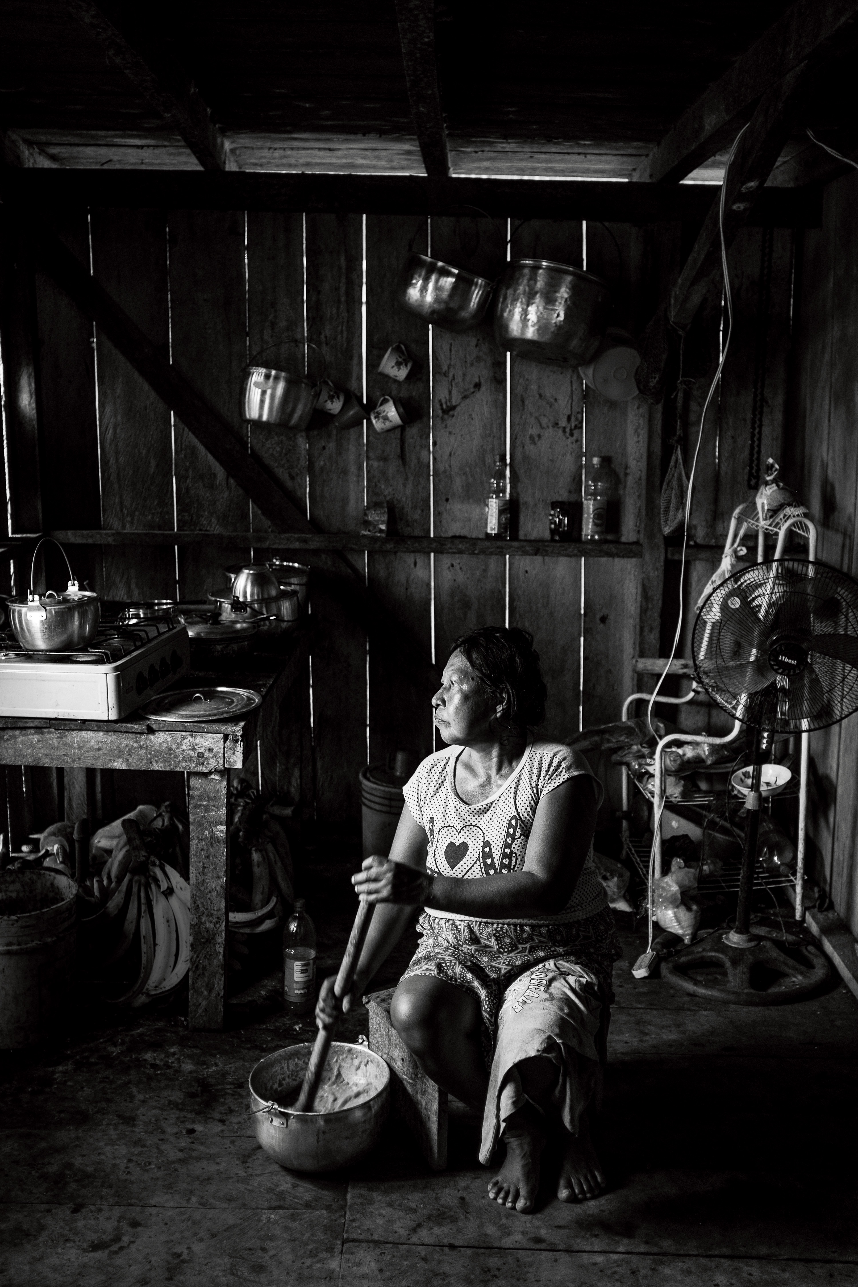 Lucia Quenamá is Alejandro's wife. She spends most of her days cooking food, washing clothes and dishes in the Aguarico River, and socializing with other women. In this photo, she is mashing ripe plantains to make cui’ccu, a sweet beverage that provides the majority of the calories the Cofán need to survive.