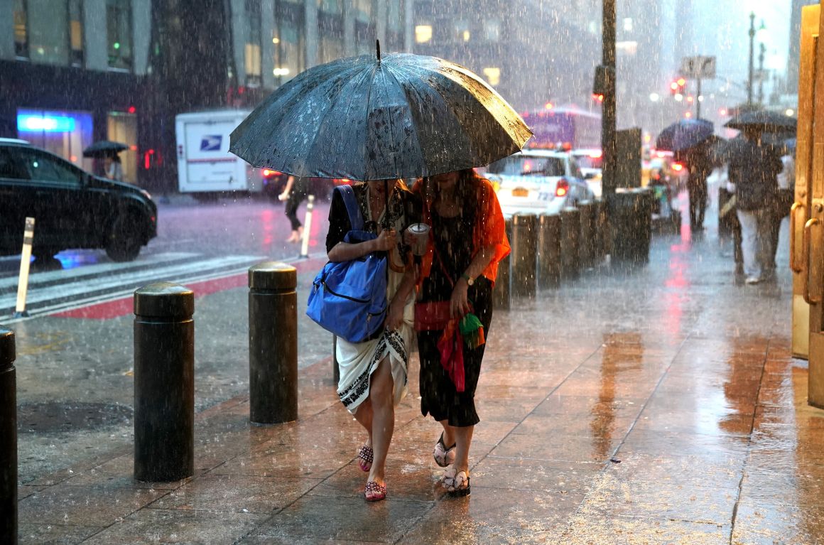 People take cover from the rain in Midtown New York on July 17th, 2018, as a sudden storm hit the area with flash food warning in the Tri-State area.