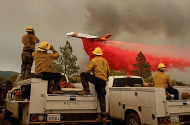 Firefighters watch as an air tanker drops fire retardant over the Ferguson Fire in the Stanislaus National Forest, near Yosemite National Park, on July 21st, 2018.