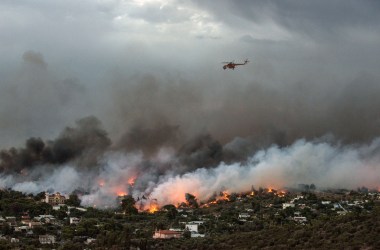 A firefighting helicopter flies over a wildfire raging in the town of Rafina near Athens, on July 23rd, 2018. At least five people have died and more than 20 have been injured as wildfires tore through woodland and villages around Athens on Monday, while blazes caused widespread damage in Sweden and other northern European nations.