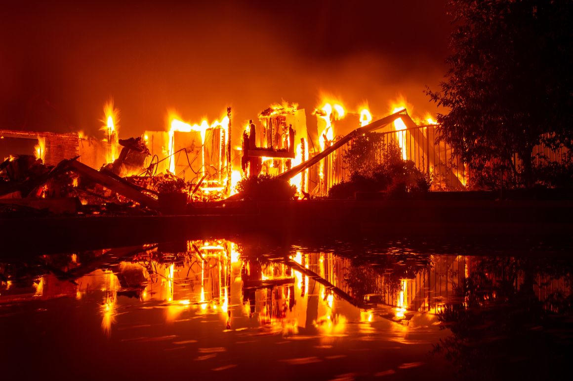 A burning home is reflected in a pool during the Carr fire in Redding, California, on July 27th, 2018.