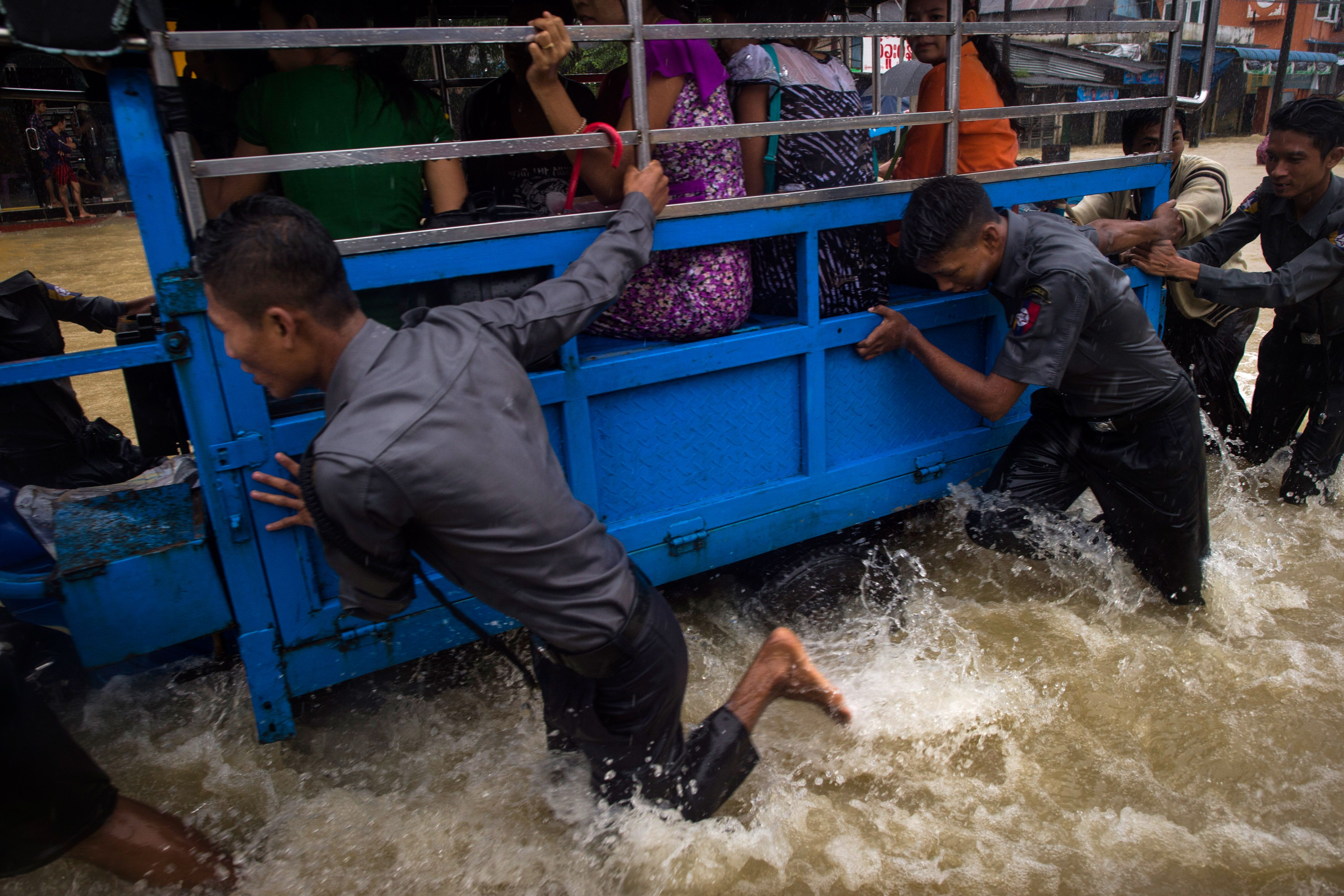 Myanmar police officers help push a tuk-tuk through floodwaters in the Bago region on July 29th, 2018.