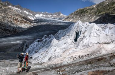 A couple take a photograph next to a part of the Rhone Glacier, covered with insulating foam to prevent it from melting, near Gletsch, Switzerland, on August 3rd, 2018, as a heatwave sweeps across northern Europe.