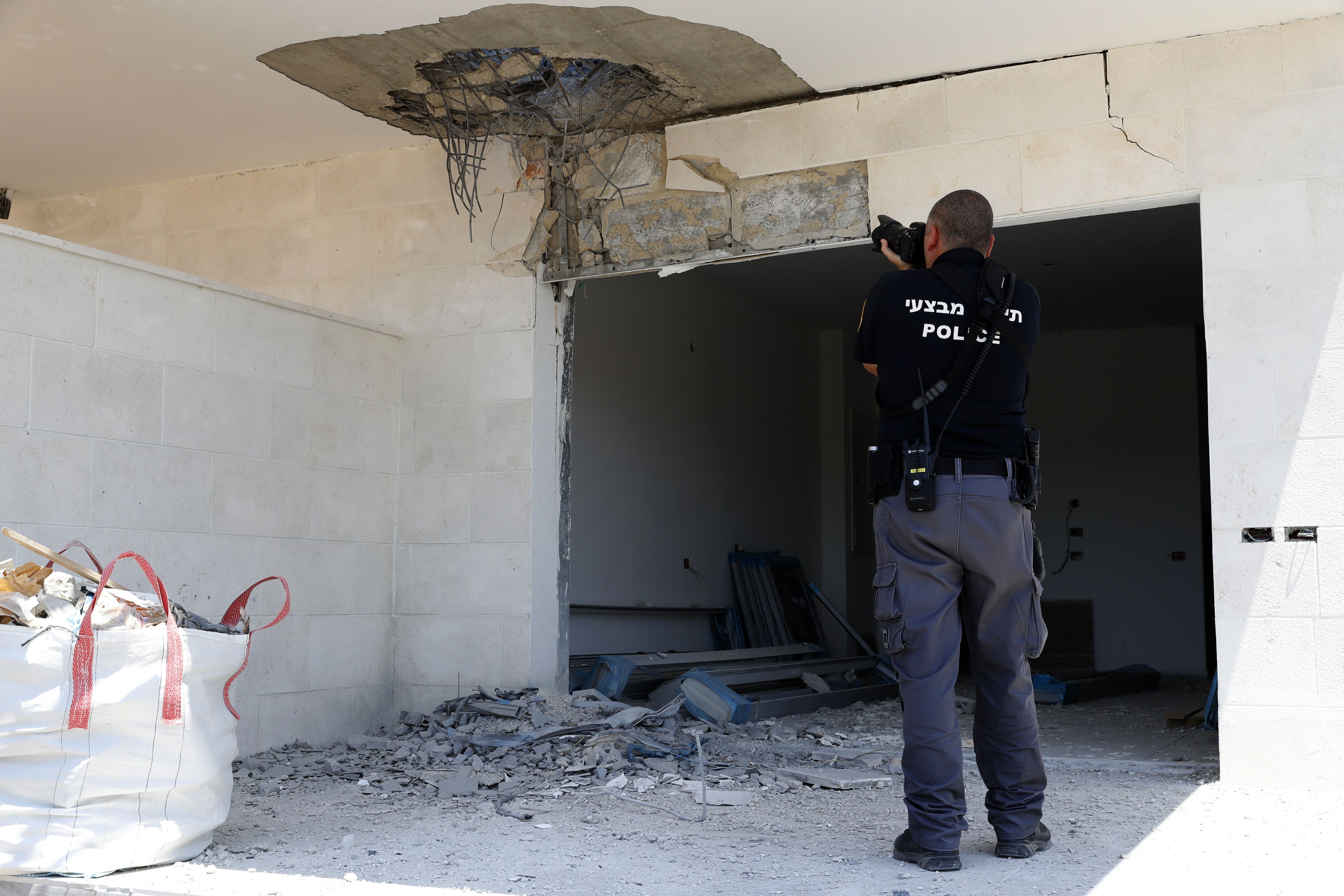 An Israeli policeman takes pictures on August 9th, 2018, of the damage in an empty house after a rocket fired by Palestinian militants from the Gaza Strip fell in the southern Israeli town of Sderot.