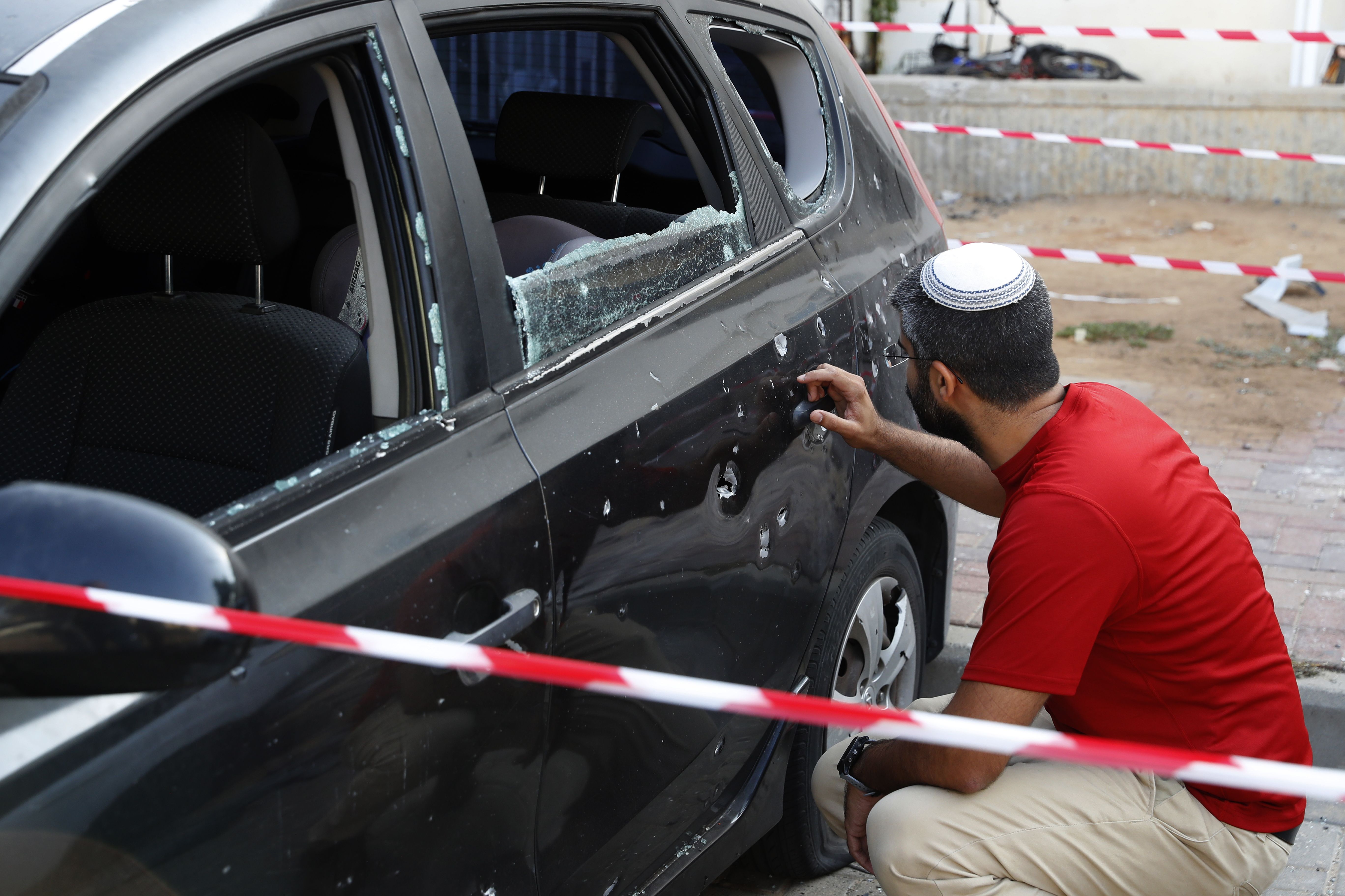 An Israeli man checks damage to his car after a rocket fired by militants from the Gaza Strip fell nearby in the southern Israeli town of Sderot on August 9th, 2018.