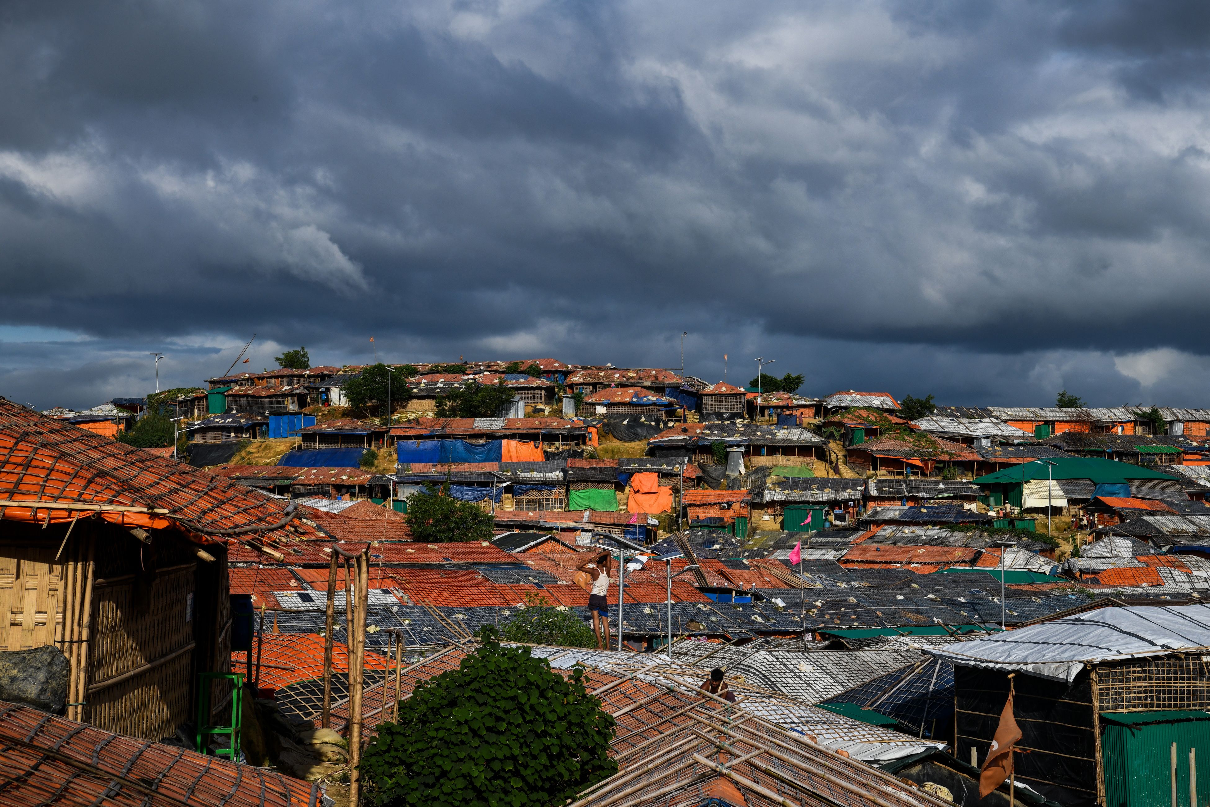 A Rohingya refugee man stands atop of a tent in Kutupalong camp in Ukhia on August 12th, 2018.