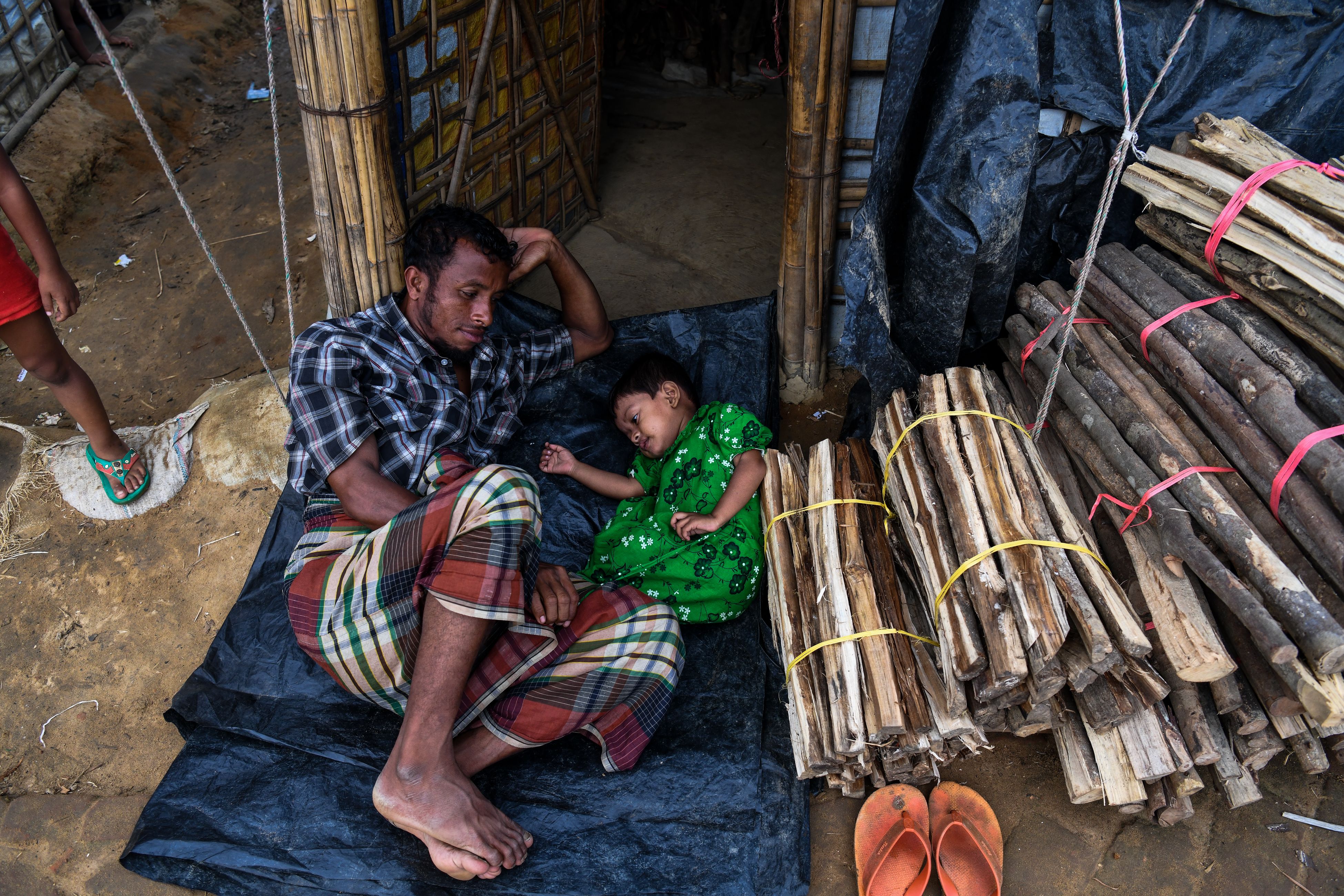 A Rohingya refugee plays with his daughter by the entrance of their tent at the Kutupalong camp in Ukhia, near the city of Cox's Bazar, on August 13th, 2018. Nearly 700,000 Rohingya fled Myanmar's Rakhine state last year to escape a violent military crackdown.