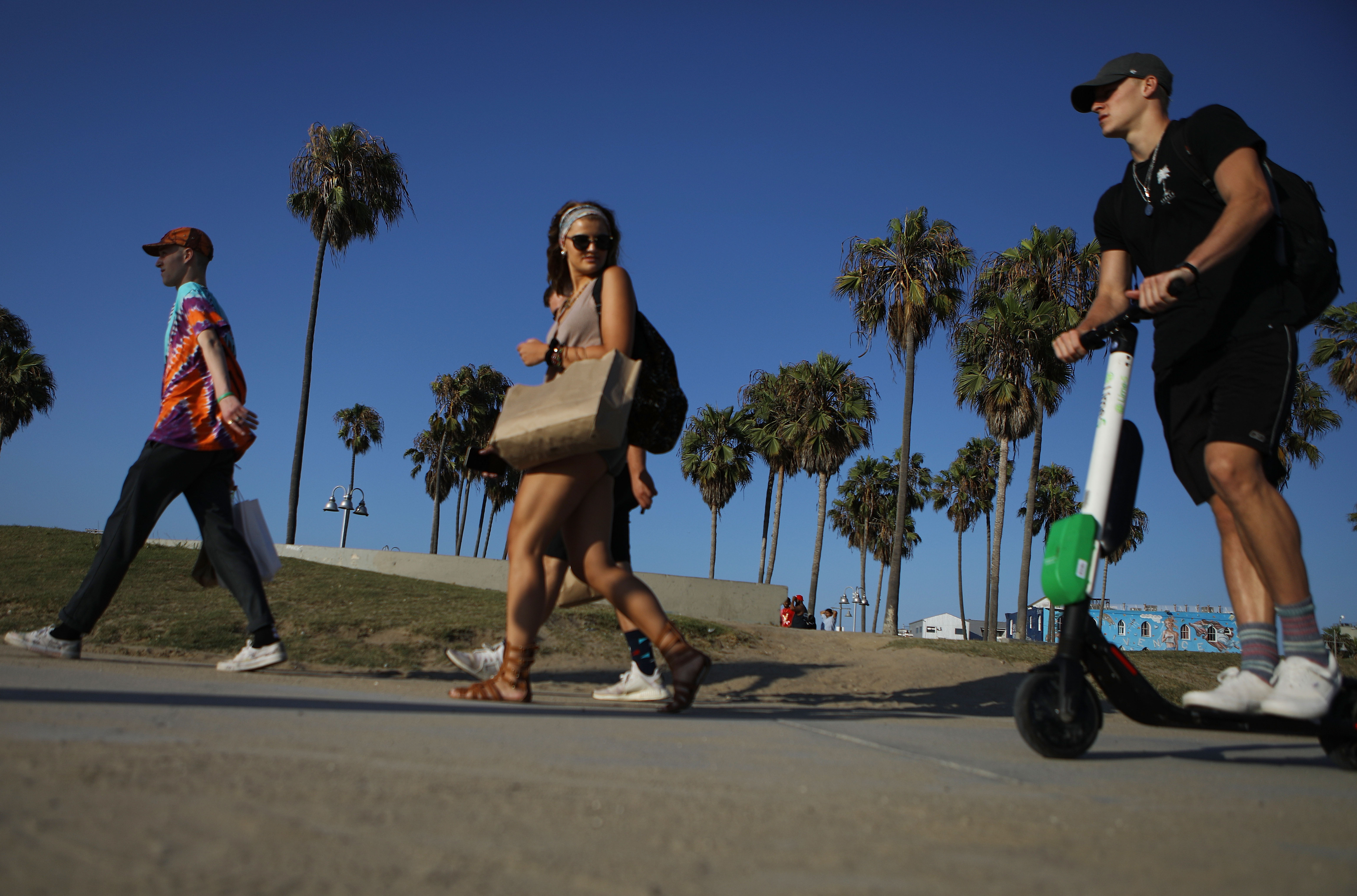 A man rides a shared dockless electric scooter along Venice Beach on August 13th, 2018, in Los Angeles, California.