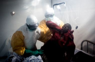 An Ebola patient is lifted up by two medical workers after being admitted into a Biosecure Emergency Care Unit (CUBE) on August 15th, 2018, in Beni, Democratic Republic of the Congo.