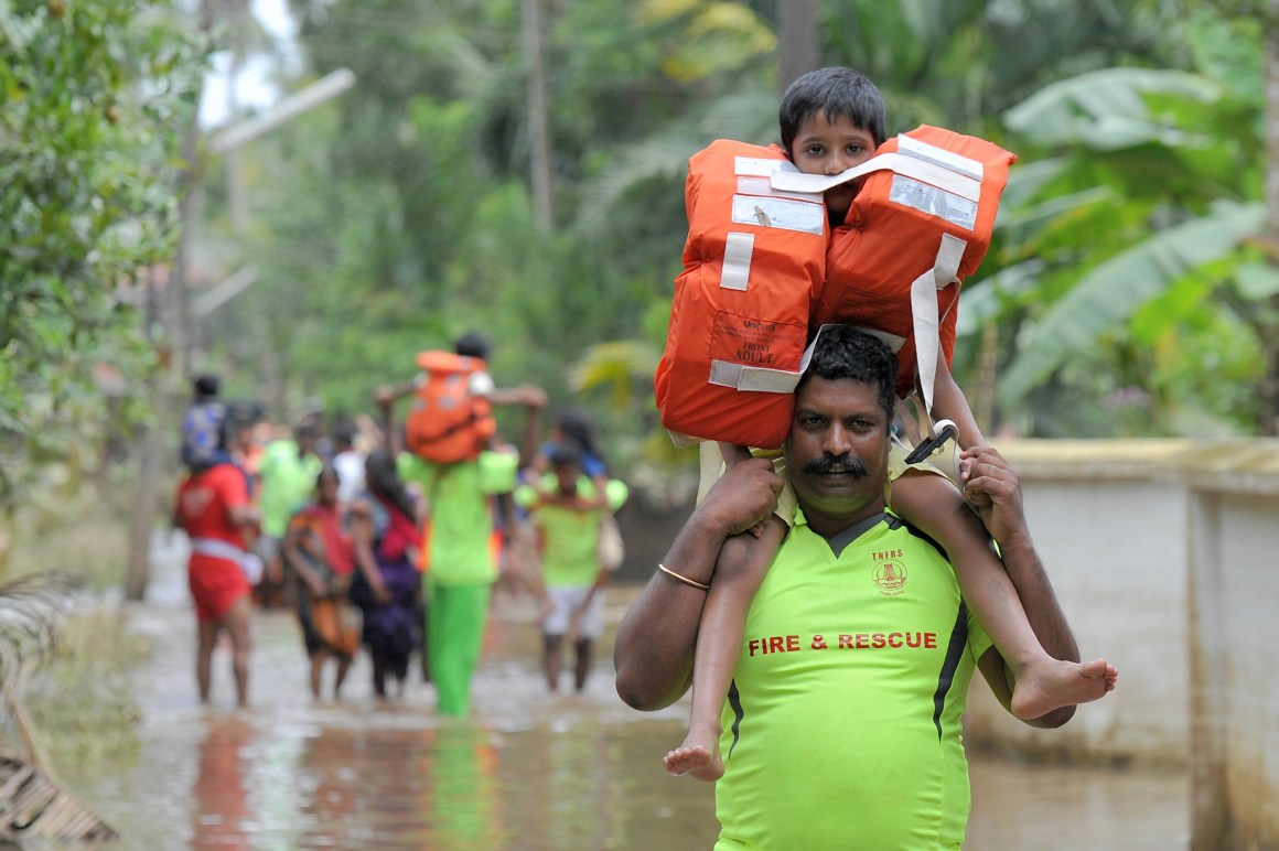 Rescue personnel carry children on their shoulders through flood waters during a rescue operation in Annamanada, a village in India, on August 19th, 2018. Rescuers waded into submerged villages in a desperate search for survivors cut off for days by floods that have already killed more than 350 people.