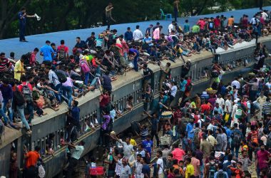 People scramble to reach the roof of an overcrowded train at a station in Dhaka, Bangladesh, on August 20th, 2018. Crowds rushed home from the capital city to be with friends and family during the annual holiday of Eid al-Adha, also known as the Festival of Sacrifice, celebrated by Muslims worldwide.