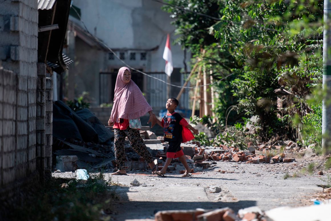 Residents walk among debris in the village of Sugian on Indonesia's Lombok Island on August 21st, 2018, after a series of recent earthquakes. Indonesian aid agencies and government officials rushed to help survivors after another series of powerful quakes rattled the island, killing at least 14 people and leaving hundreds of thousands homeless.