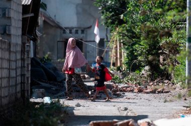 Residents walk among debris in the village of Sugian on Indonesia's Lombok Island on August 21st, 2018, after a series of recent earthquakes. Indonesian aid agencies and government officials rushed to help survivors after another series of powerful quakes rattled the island, killing at least 14 people and leaving hundreds of thousands homeless.