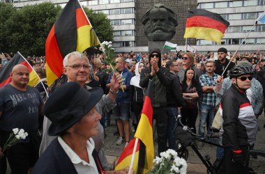 People holding German flags arrive at a right-wing protest gathering near a statue of Karl Marx the day after a man was stabbed and died of his injuries on August 27th, 2018, in Chemnitz, Germany. A German man died after being stabbed in the early hours of August 26th following an altercation, leading a xenophobic mob of approximately 800 people to take to the streets. Left- and right-wing groups of over a thousand people each confronted each other as riot police stood in between.