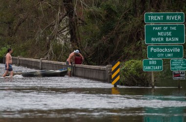 Two men pulling a kayak pick up a gas canister as they walk across a road flooded by Hurricane Florence in Pollocksville, North Carolina, on September 16th, 2018.