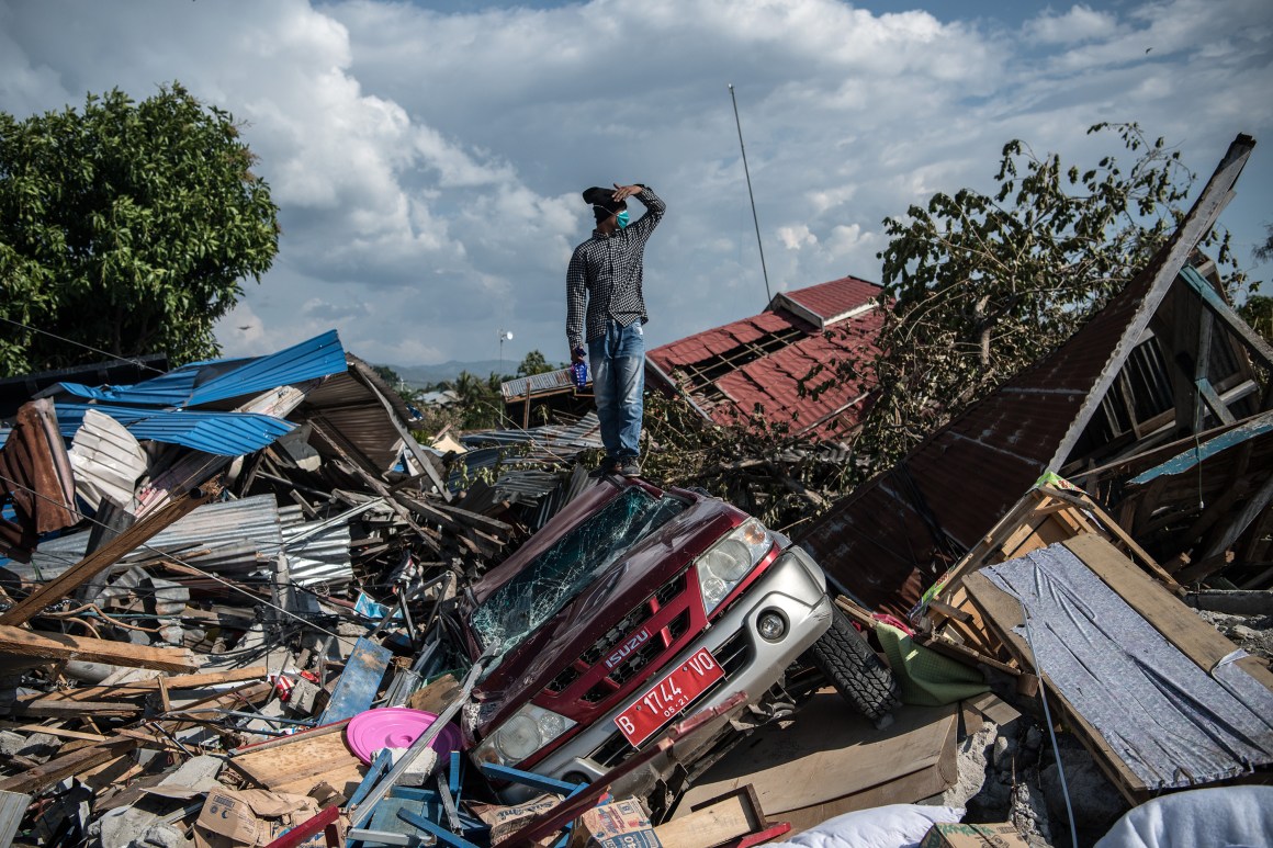 A man stands on a destroyed car as he views the rubble and debris of destroyed buildings following an earthquake, on October 2nd, 2018, in Palu, Indonesia.