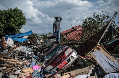 A man stands on a destroyed car as he views the rubble and debris of destroyed buildings following an earthquake, on October 2nd, 2018, in Palu, Indonesia.