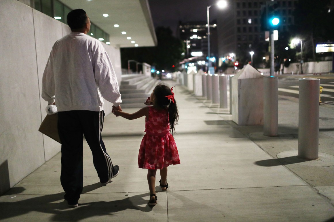 A Honduran man walks with his daughter near Metropolitan Detention Center on October 2nd, 2018, in Los Angeles, California.