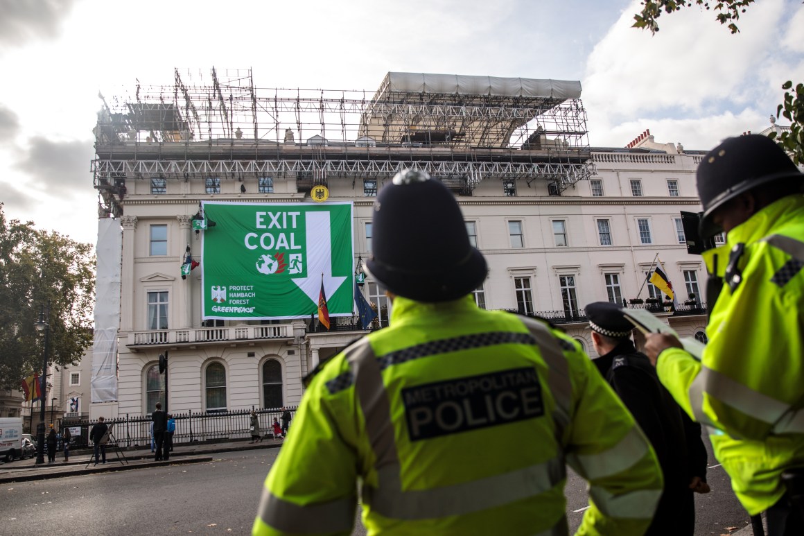 Police officers look on as Greenpeace activists hang from ropes after unfurling a banner outside the German embassy in a protest against coal on October 8th, 2018, in London, England. The stunt by the environmental campaign group came on the day that a report was released by the United Nations' top climate science panel calling for accelerated action to tackle climate change.