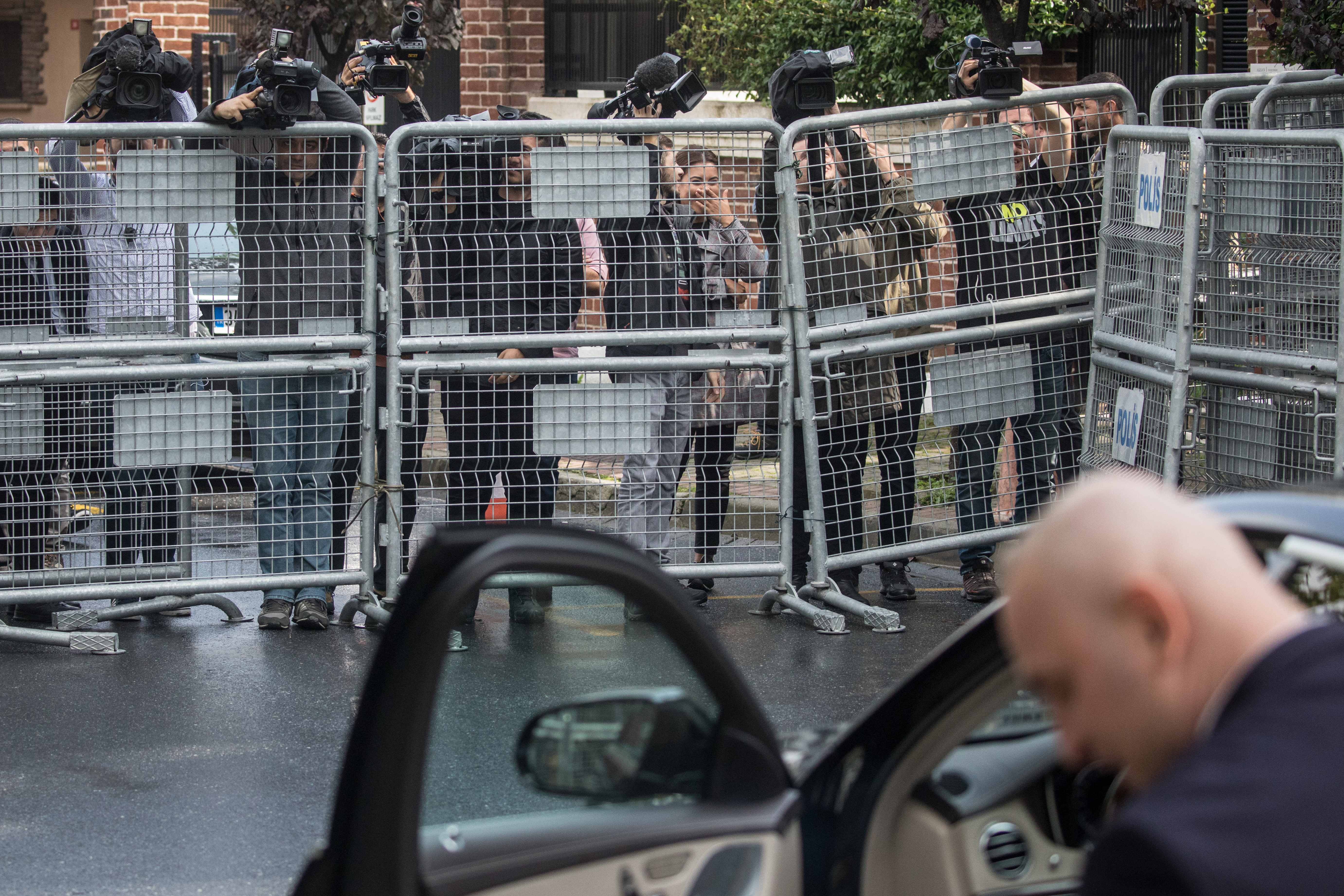 Members of the press film over a police barricade as a driver waits to take a passenger from the entrance of Saudi Arabia's consulate on October 11th, 2018, in Istanbul, Turkey.