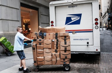 A US Postal worker delivers Amazon boxes outside of the New York Stock Exchange on October 11th, 2018 in New York City.