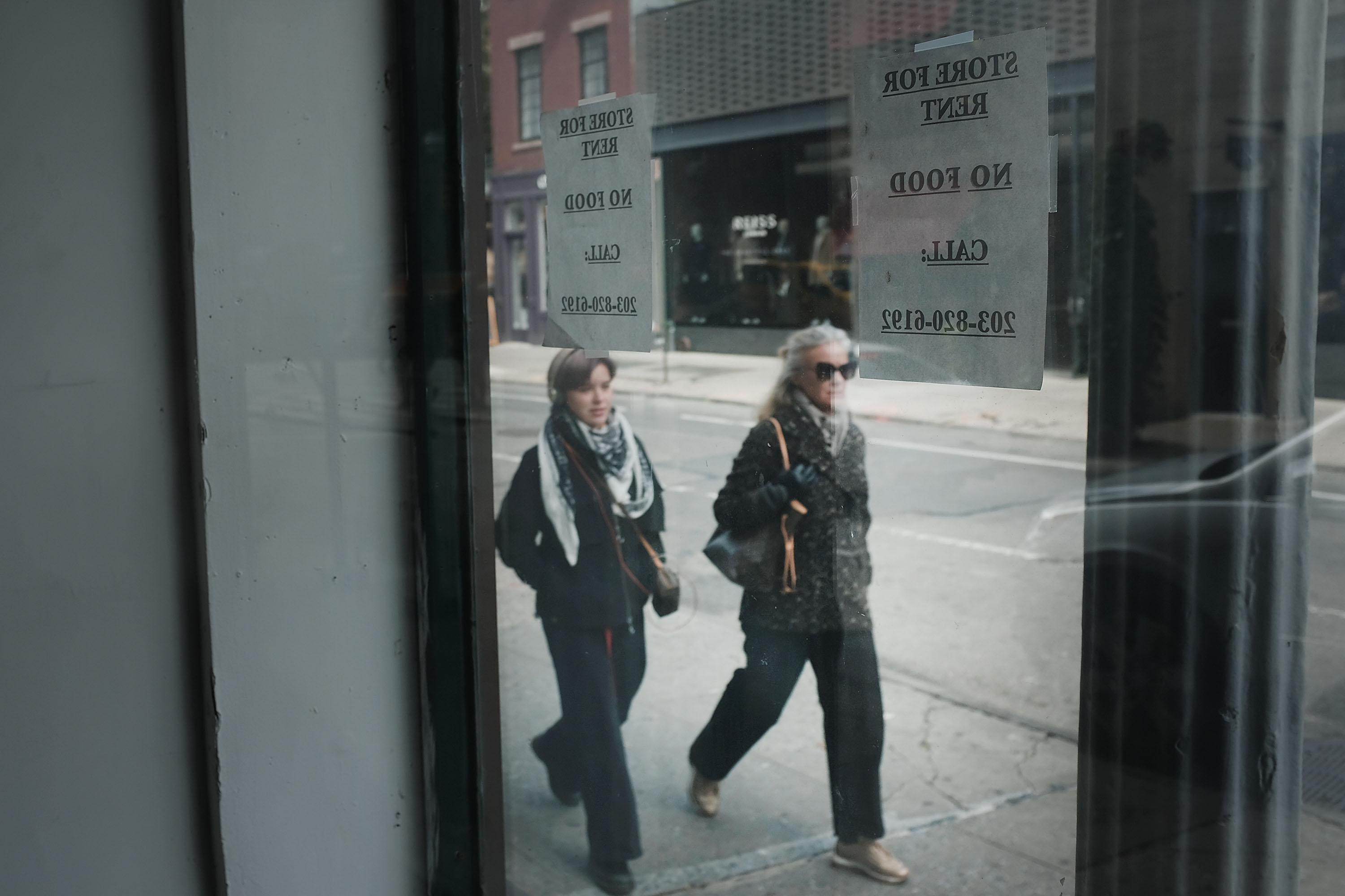 People walk by an empty store along a block in the West Village of Manhattan on October 16th, 2018.