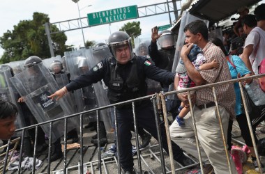 A Mexican riot policeman protects an immigrant father and child during a clash between police and the migrant caravan on the border between Mexico and Guatemala on October 19th, 2018, in Ciudad Tecun Uman, Guatemala.