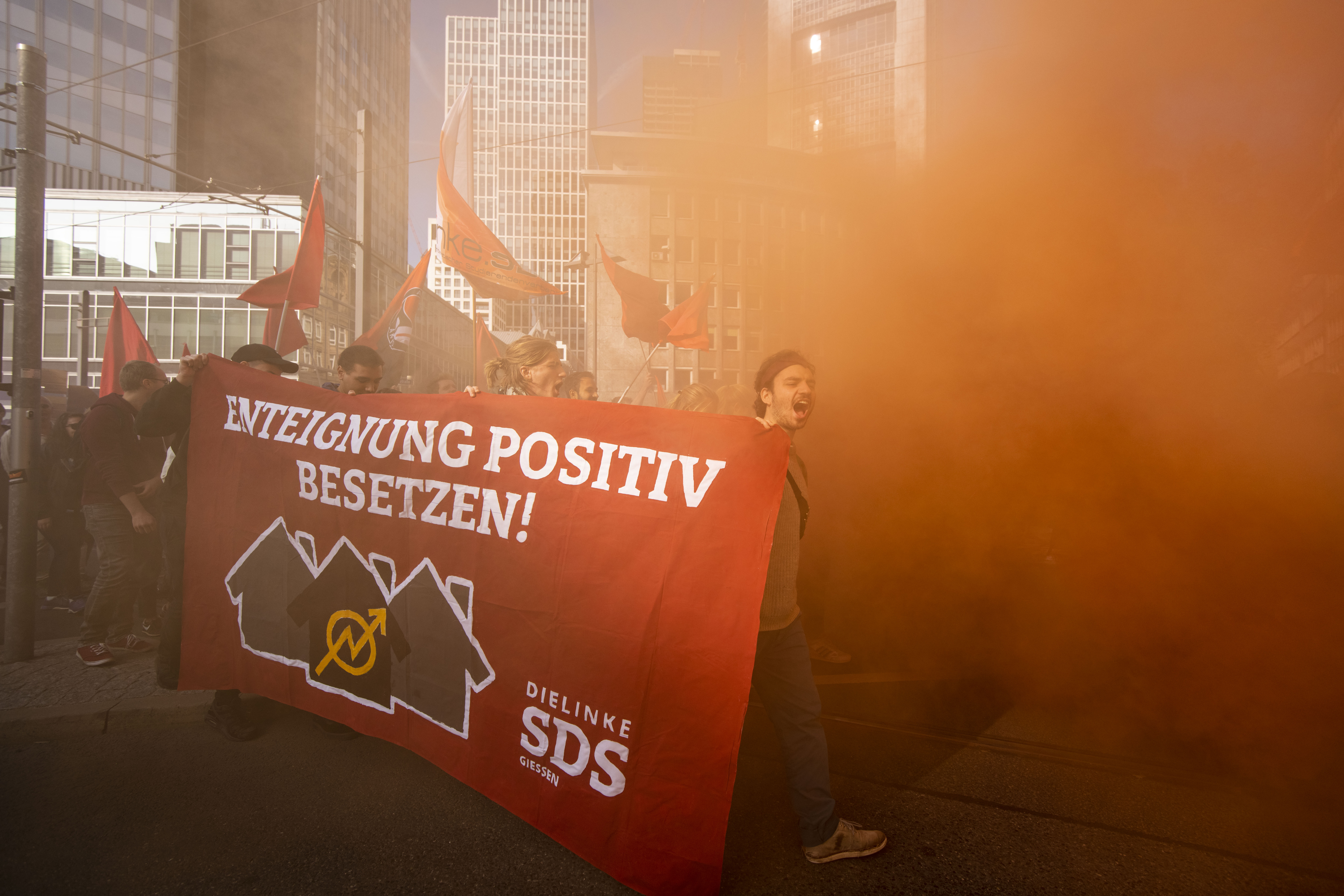 Protesters walk in the smoke while demonstrating against rising housing rental prices on October 20th, 2018, in Frankfurt, Germany. Skyrocketing costs for housing have become a major issue in cities across Germany, with local government scrambling to find policy solutions. Frankfurt in particular is already attracting wealthy newcomers as the city becomes an alternative for companies in the financial sphere relocating from Brexit-afflicted London. In other cities, especially Berlin, foreign investors, including from China, are parking their money in luxury apartment purchases.