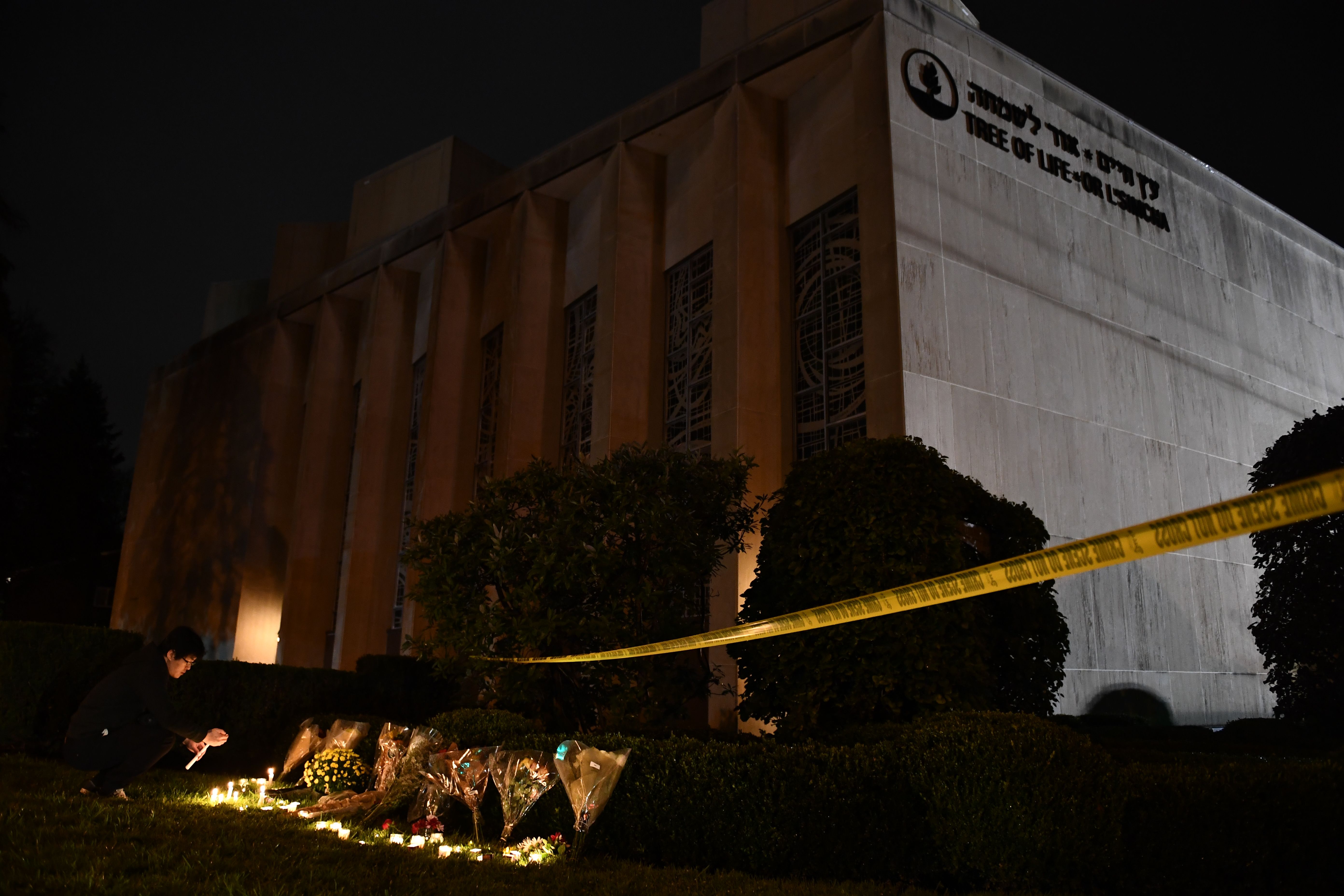 A man kneels to light a candle beneath police tape outside the Tree of Life Synagogue after a shooting there left 11 people dead in the Squirrel Hill neighborhood of Pittsburgh on October 27th, 2018. A heavily armed gunman opened fire during a baby-naming ceremony at the synagogue in Pittsburgh's Squirrel Hill neighborhood in the deadliest anti-Semitic attack in recent American history.