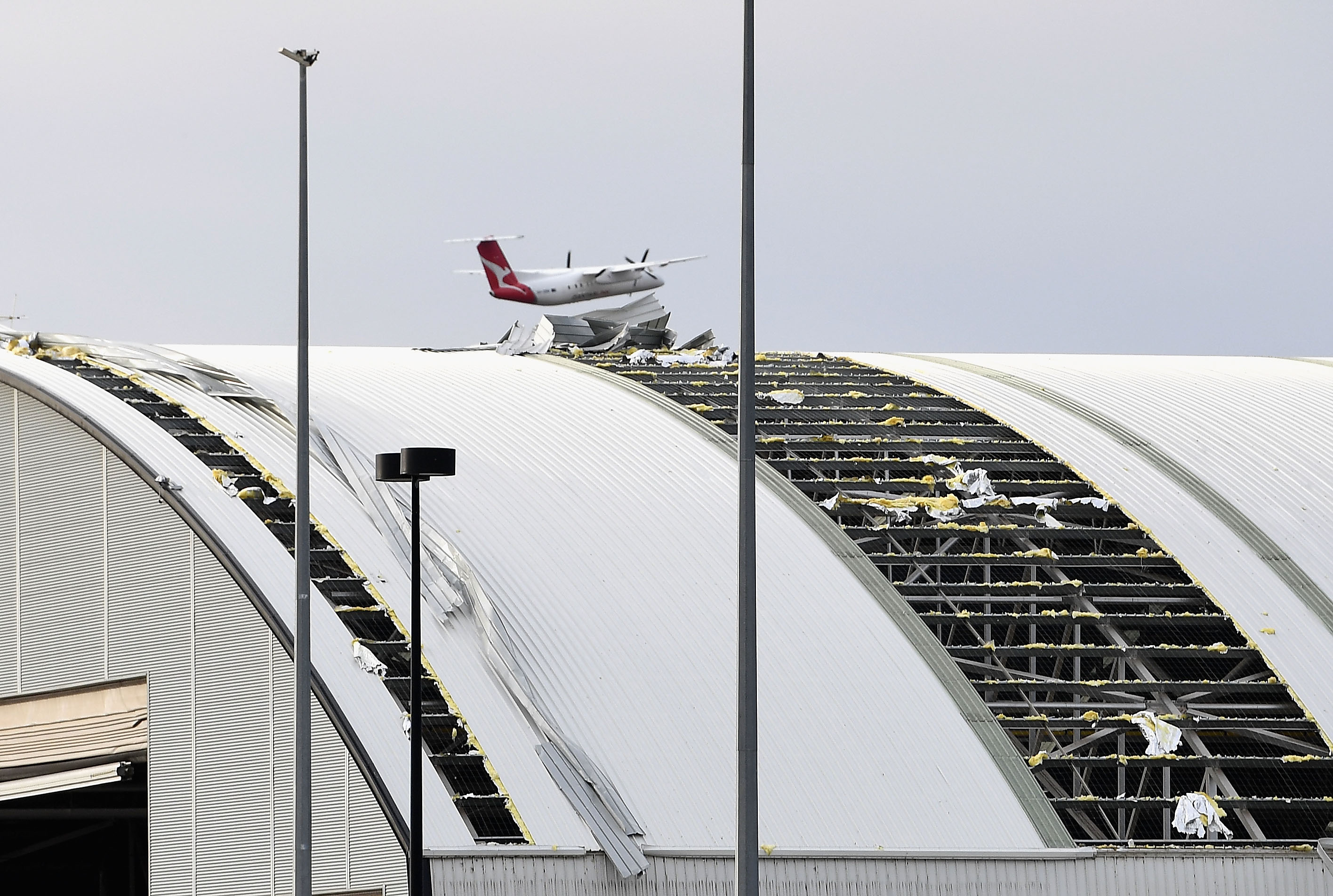 A plane flies over a damaged airport hangar roof that was ripped off in the storm that hit Canberra, Australia, on November 2nd, 2018. Strong winds and a thunderstorm swept through the state late in the afternoon.