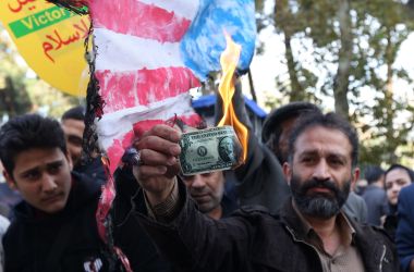 On the eve of renewed sanctions by Washington, An Iranian protester burns a dollar banknote during a demonstration outside the former U.S. embassy in the Iranian capital of Tehran.