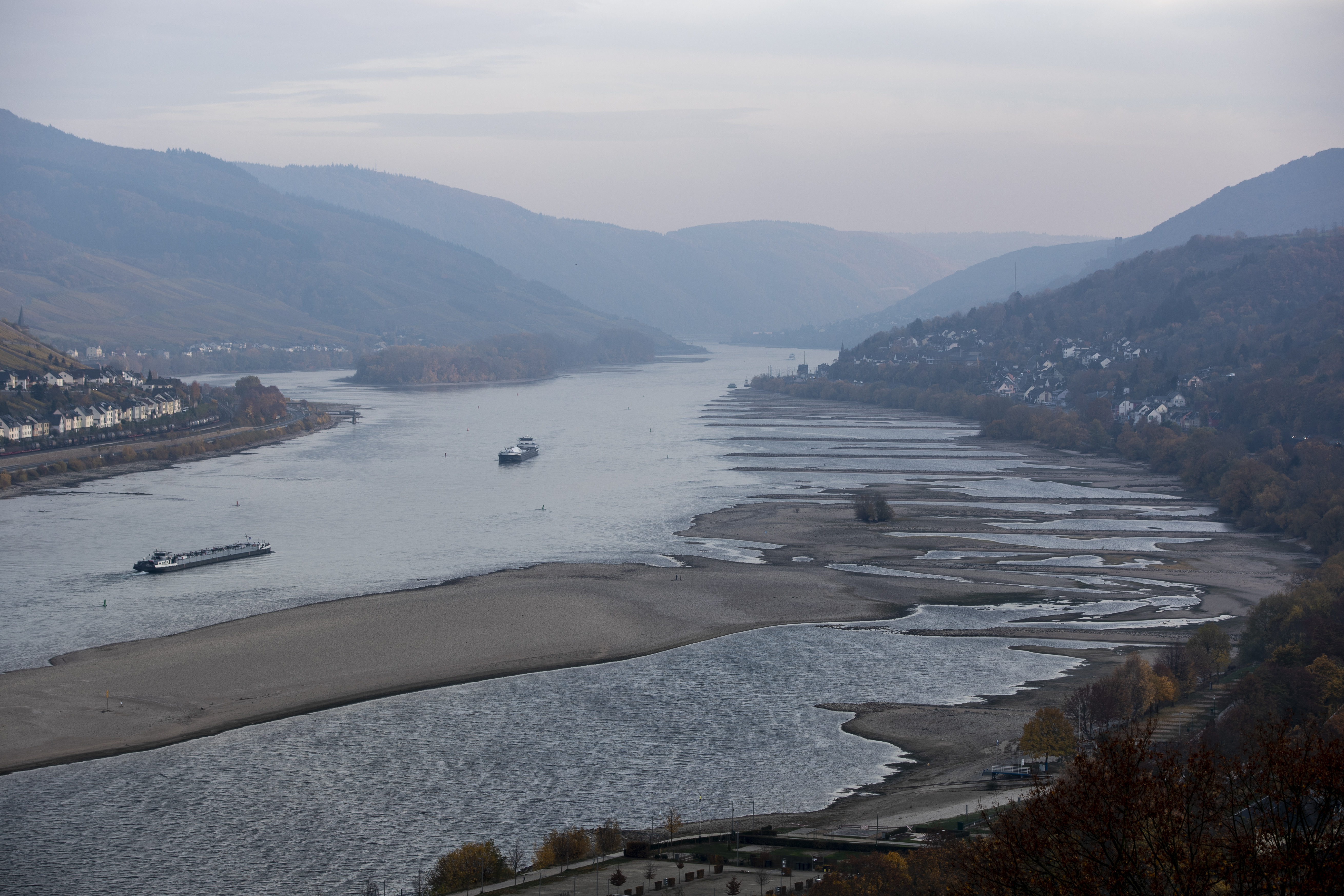 Cargo ships maneuver near the banks of the Rhine River on November 9th, 2018, near Kaub in Germany. The summer heat wave in Germany, unfavorable wind conditions, and no rain left the Rhine—which begins in the Swiss Alps, runs through Germany, and empties into the North Sea—at record low water levels. This created problems in the shipping industry, brought environmental damage, caused oil prices to rise, and meant billions of euros of losses. Although rainfall is expected soon, experts warn it will probably take weeks or months to bring water levels in the river, Germany's most important waterway and a key shipping route for the Netherlands and France, back to normal.