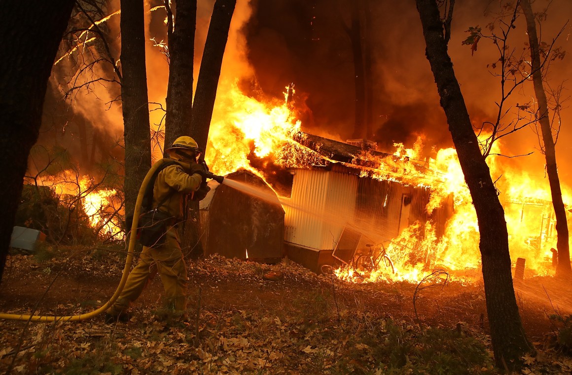 A California Department of Forestry and Fire Protection firefighter monitors a burning home as Northern California's Camp Fire moves through the area on November 9th, 2018, in Magalia, California. Fueled by high winds and low humidity, the rapidly spreading fire ripped through the town of Paradise and quickly charred 70,000 acres. It destroyed numerous homes and businesses in a matter of hours.