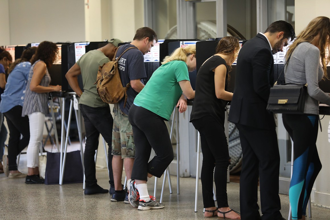 Voters fill out their ballots as they cast their vote at a polling station setup in Legion Park for the mid-term election on November 6th, 2018 in Miami, Florida.