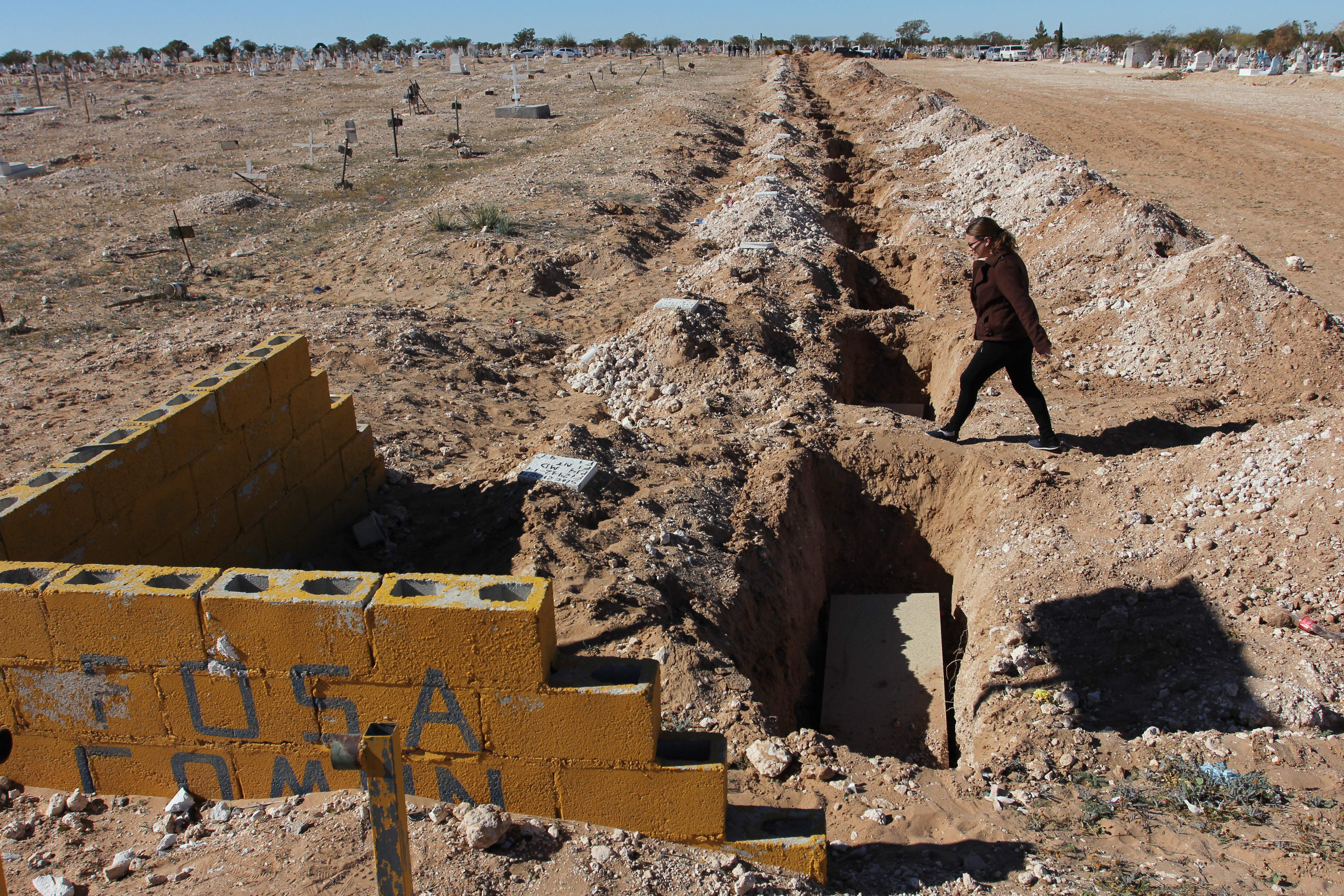 A woman walks near a common grave during the burial of 25 unidentified or unclaimed corpses at the San Rafael municipal pantheon in Ciudad Juarez, Chihuahua state, Mexico, on November 28th, 2018.