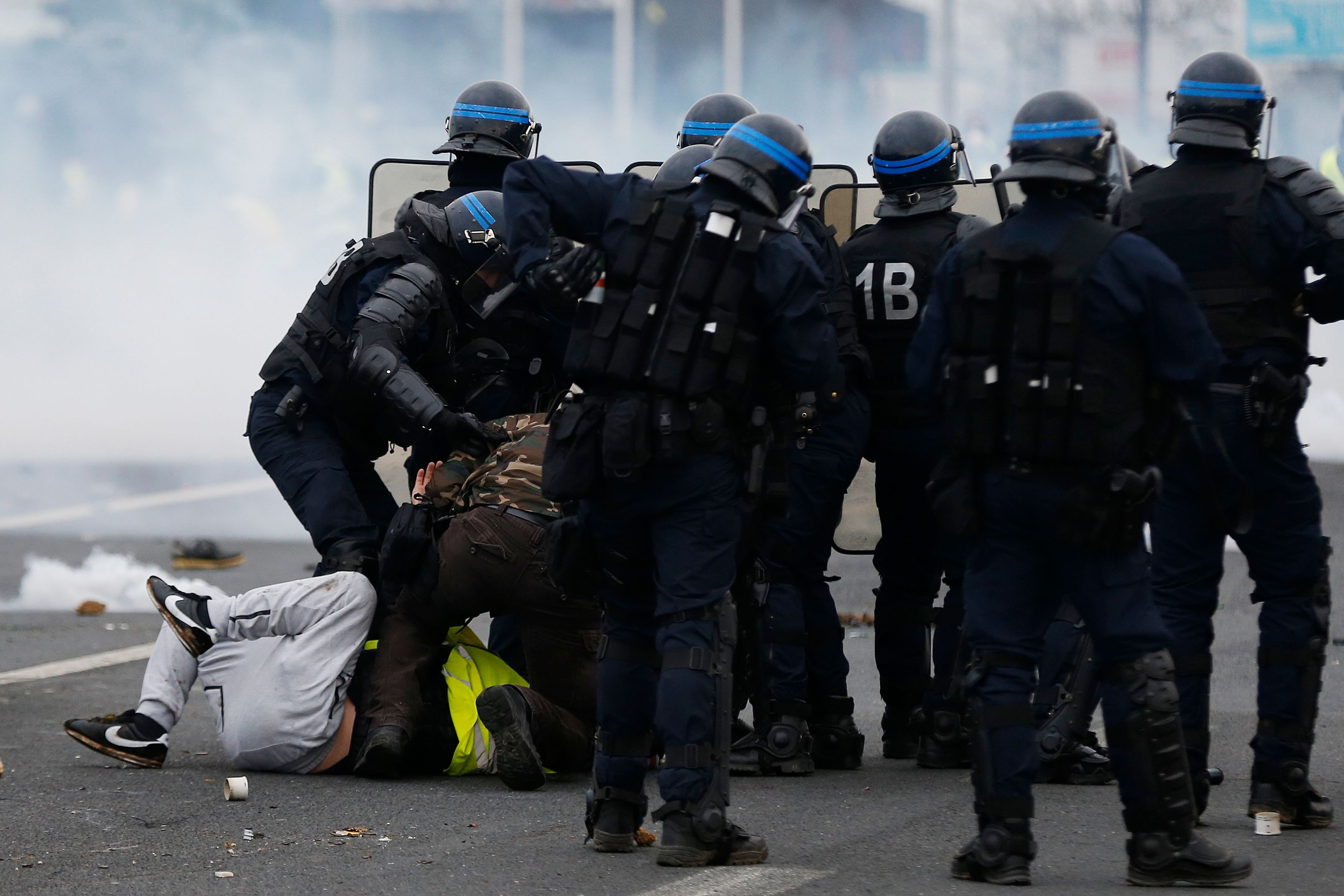 French riot police officers detain protesters during a 