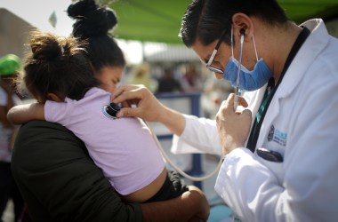 A Honduran mother holds her daughter, who fell ill, while being examined by a doctor outside a shelter for migrants on November 21st, 2018, in Mexicali, Mexico.