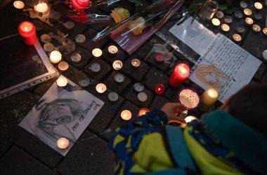 A man lights candles at a vigil on December 13th, 2018, in memory of the victims of an attack near the Christmas market of Strasbourg in France. Officials say three people were killed and 13 wounded when a lone gunman, identified as Cherif Chekatt, 29, opened fire on shoppers on December 11th.