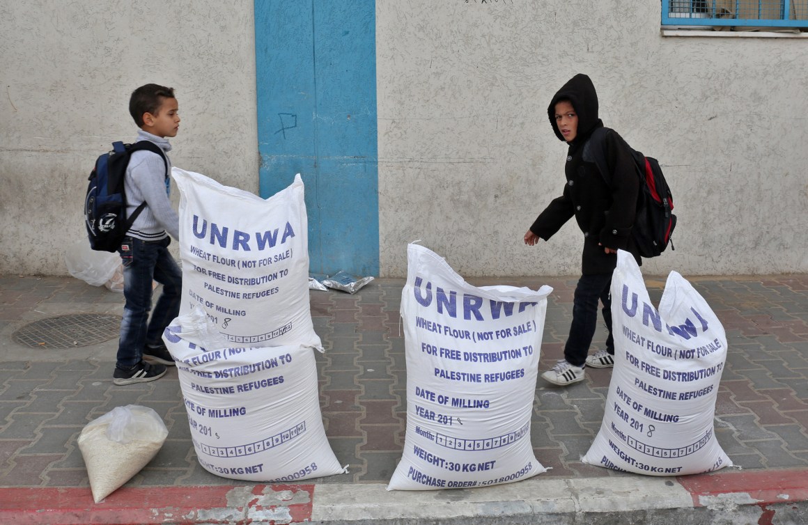 Palestinian schoolboys walk past sacks of flour outside an aid distribution center run by the United Nations Relief and Works Agency, in Rafah in the southern Gaza Strip, in December of 2018.