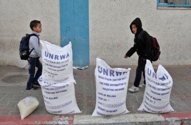 Palestinian schoolboys walk past sacks of flour outside an aid distribution center run by the United Nations Relief and Works Agency, in Rafah in the southern Gaza Strip, in December of 2018.