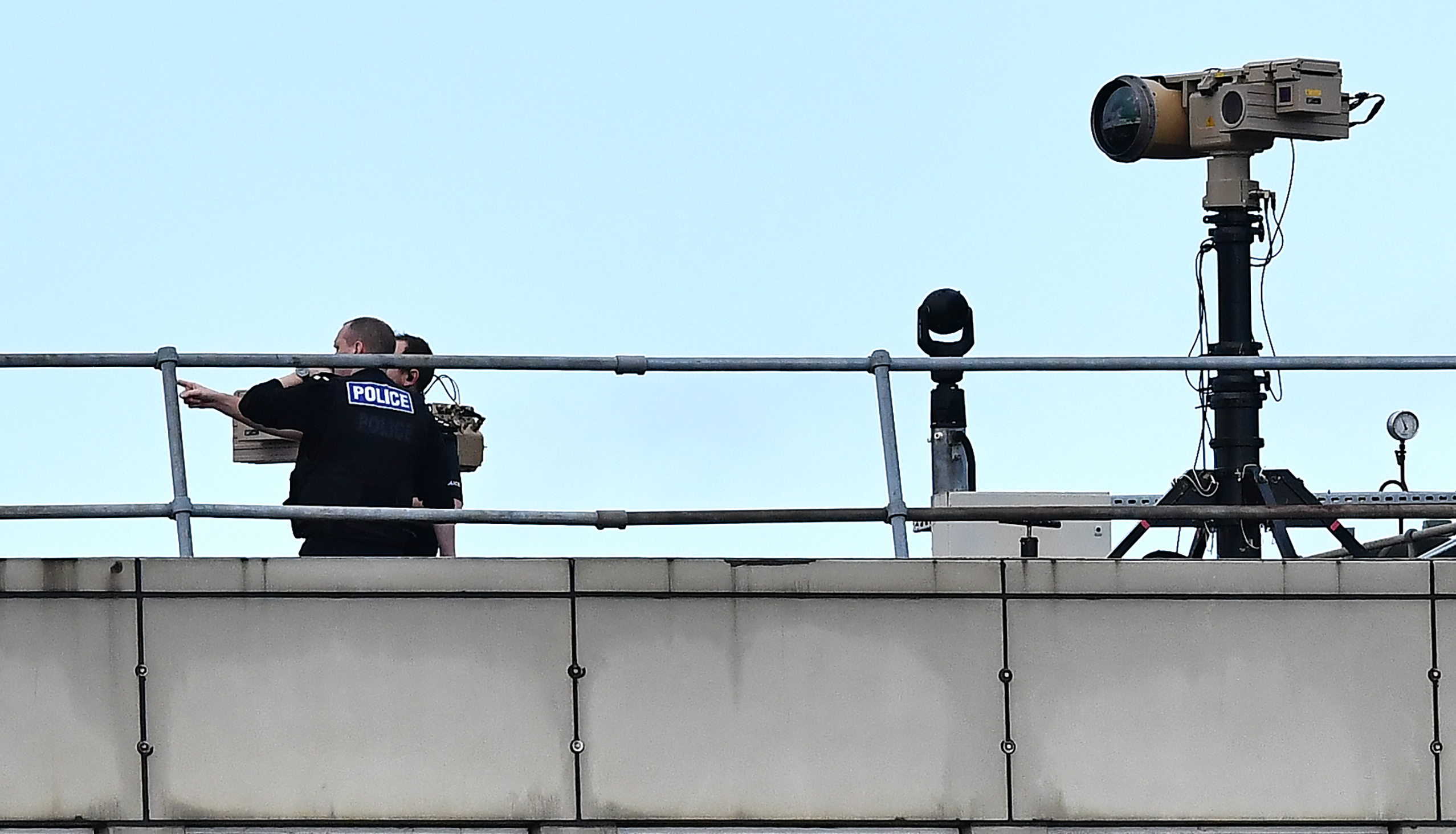 Police officers stand near equipment on the rooftop of a building at Gatwick Airport on December 21st, 2018.