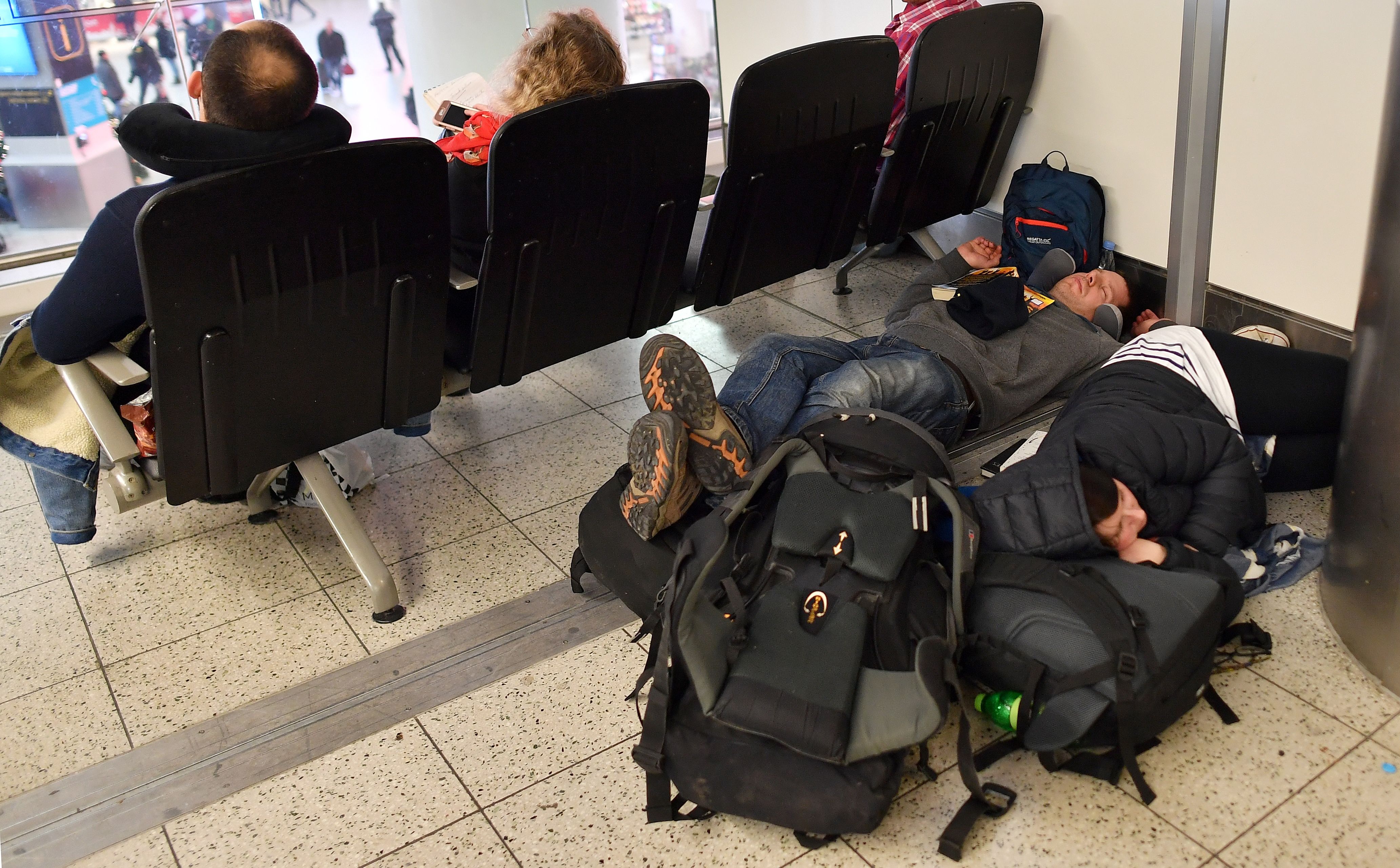 Passengers lay on the floor with their luggage in the South Terminal building at London Gatwick Airport, south of London, on December 21st, 2018, as flights started to resume following the closing of the airfield. British police on Friday were considering shooting down the drone that has grounded flights and caused chaos at the airport, with passengers set to face a third day of disruption. Police said it was a 