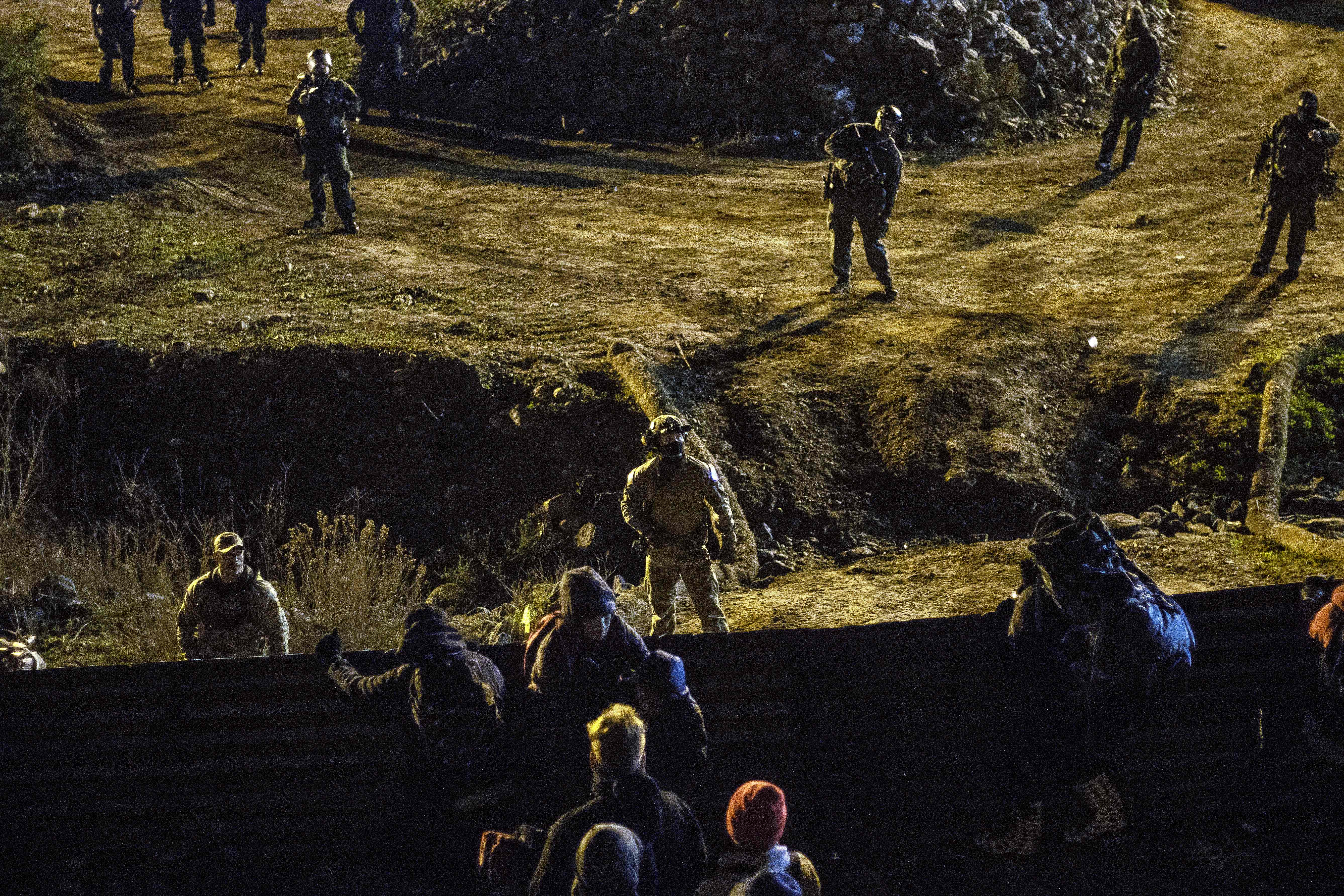 US border patrol officers deploy near the US-Mexico border fence to deter Central American migrants from crossing from Tijuana to San Diego, as seen from Tijuana, Baja California state, Mexico on January 1, 2019. - Around 100 Central American migrants made a failed attempt on New Year's Eve to cross over from Mexico into the United States. As night fell and people on both sides of the frontier prepared to celebrate New Year's Eve, the migrants tried to cross over but at least two smoke bombs were hurled and they ultimately held back.