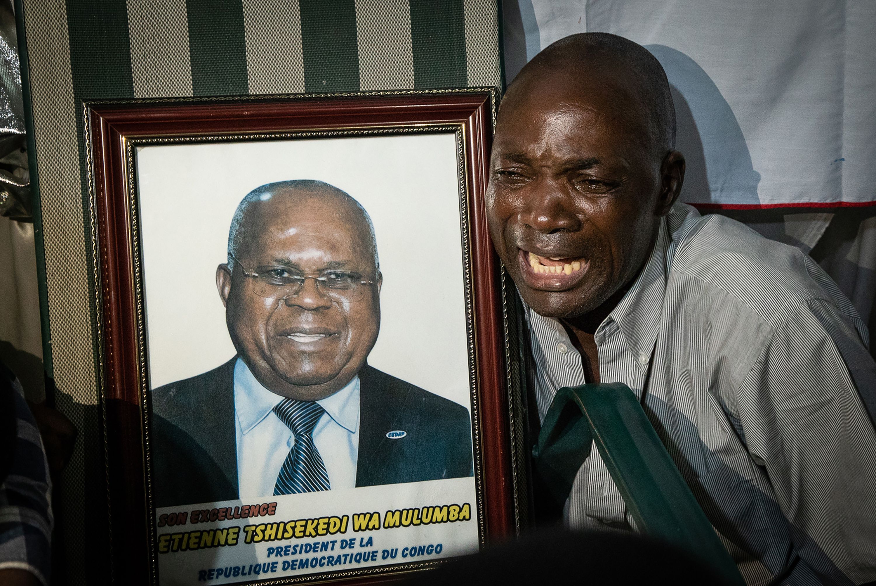 A supporter of Felix Tshisekedi reacts next to a picture of Etienne Tshisekedi, a Congolese political opponent who died in February of 2017 and father of the current candidate, after Felix Tshisekedi was named the provisional winner in the presidential election, at the former residence of Etienne Tshisekedi in Kinshasa on January 10th, 2019.