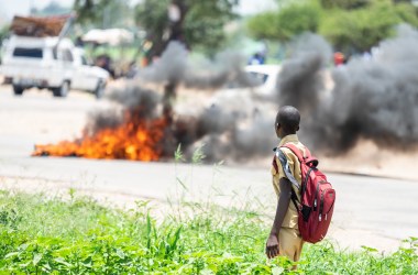 A school boy looks at a burning barricade during a demonstration on January 14th, 2019, in Bulawayo, Zimbabwe. Angry protesters barricaded roads with burning tires and rocks after the government more than doubled the price of fuel in a bid to improve supplies as the country battles its worst gasoline shortage in a decade.