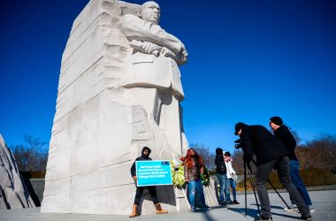 People visit the Martin Luther King Jr. Memorial in Washington, D.C., for Martin Luther King Day on January 21st, 2019. The man holds a sign that quotes Martin Luther King Jr. It reads, "Our lives begin to end the day we become silent about things that matter."