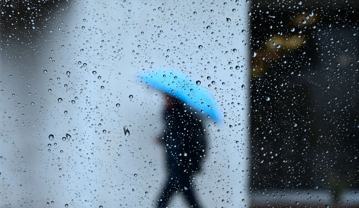 Raindrops are seen on a vehicle window as a pedestrian walks in the rain in Los Angeles, California on January 31st, 2019, as heavy rains hit southern California bringing thunder and lightning.