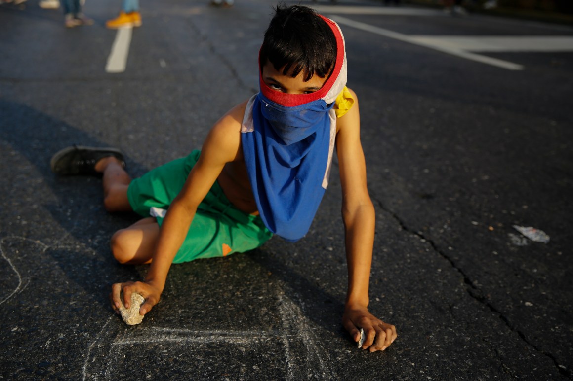 A young demonstrator writes slogans on the pavement during a protest against the government of President Nicolás Maduro in the streets of Caracas, Venezuela, on February 2nd, 2019.