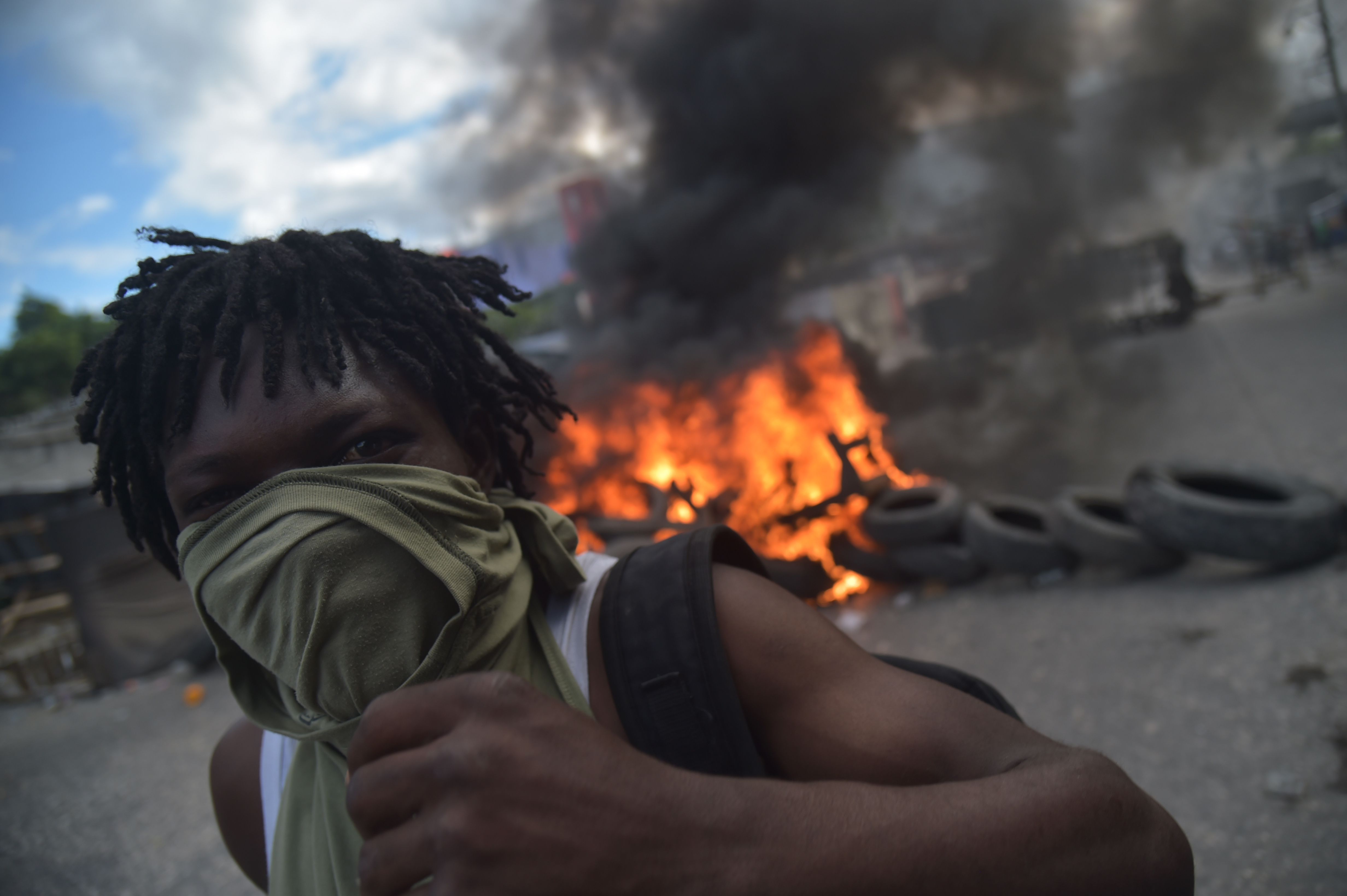 A demonstrator stands before a barricade of burning tires on the fourth day of protests in Port-au-Prince, Haiti, on February 10th, 2019. Demonstrators are demanding the resignation of Haitian President Jovenel Moise and protesting the misuse of nearly  billion from the PetroCaribe fund.